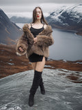 Model walking in Raccoon Glamour Jacket - Mountain Mirage S/M across mountain plateau, showcasing fur coat in motion.