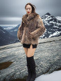 Model posing in Raccoon Glamour Jacket - Mountain Mirage S/M on rocky slope, highlighting fur detail and luxury outerwear appeal.