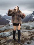 Model in Raccoon Glamour Jacket - Mountain Mirage S/M dancing on rocky terrain, highlighting movement and warmth of real fur coat.