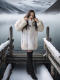 Woman in a fur coat standing on a snowy dock with a snowy landscape in the background