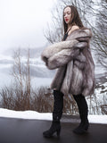 Real fur blue fox coat with natural silver tones, modeled on a snowy road. Plush and warm outerwear for luxury winter fashion.