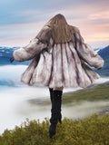 Back view of plush blue fox coat with fully let out pelts and wide silhouette, worn above a cloud-filled valley. Luxury fur outerwear.