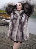 Luxury blue fox fur coat with wide shawl collar and full sleeves, displayed in a dramatic pose by a mountain lake. Real fur outerwear for cold climates.