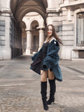 Model twirls in The Still Hour deep teal fur coat, revealing its flowing cut and plush texture for statement winter outerwear.