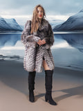 Woman in a fur coat and black boots standing in a snowy landscape.