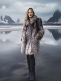 Woman in a fur coat standing in a snowy landscape with mountains.