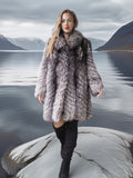 Woman in a fur coat standing on a rock with a scenic mountain and lake background