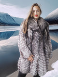 Woman wearing a fur coat standing in a snowy landscape with mountains in the background