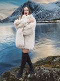 Model posing by a lake in Soft Plush Blush Fox Jacket S/M, showcasing thick fox fur and cozy shawl collar for winter fashion.