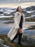 Model smiling in Two Tone Fox Coat Size XS/S with chevron fur pattern, styled in a rocky winter landscape for chic outerwear fashion.