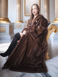 Woman wearing a long brown fur coat in an elegant interior setting.