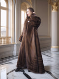 Woman wearing a long brown fur coat in an elegant interior setting.