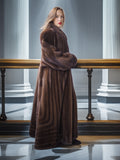 Woman wearing a long brown fur coat in an elegant interior setting with columns.
