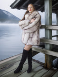 Woman in a fur coat standing on a wooden dock by a lake