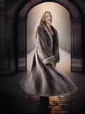Woman in a long fur coat standing in an archway with a blurred background