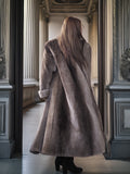 Person wearing a long fur coat standing in an ornate hallway