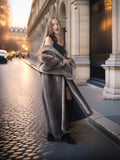 Woman in a long fur coat standing on a city street with classical architecture.