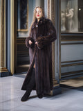 Woman wearing a long brown fur coat in an elegant interior setting.