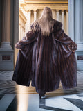 Person wearing a fur coat walking through an elegant interior setting