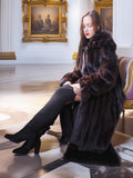 Woman in a fur coat sitting in an elegant room with classical paintings.
