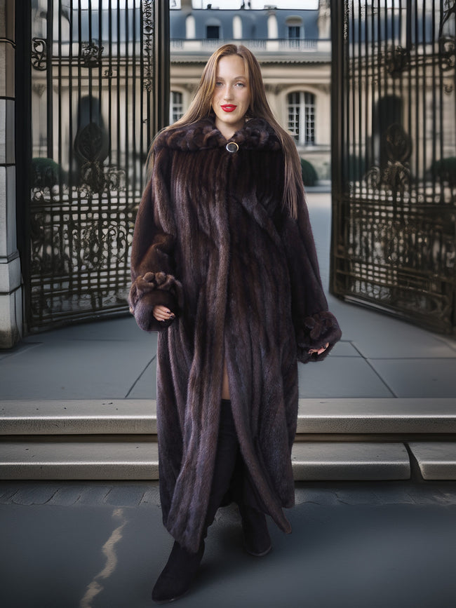 Woman wearing a fur coat standing in front of a large metal gate.