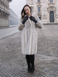 Model adjusts gloves while wearing Sapphire Grey Mink Fur Coat S Petit Excellent, ideal for sustainable and elegant winter fashion.
