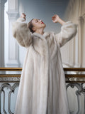 Woman wearing a long fur coat in an elegant interior setting
