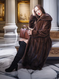 Woman in a brown fur coat holding a handbag in an elegant interior setting.