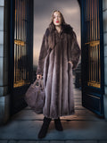 Woman in a long fur coat standing in front of ornate doors.
