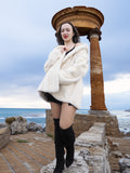 Beige Pearl Mink Fur Coat with hood, worn by a model near ancient ruins. Elegant and warm outerwear with hook-eye closure and satin lining.