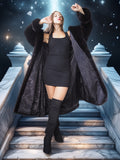 Woman in a black coat and dress standing on stone steps with a starry night sky background