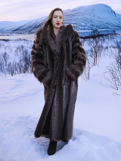 Full-length Canadian Raccoon Fur Coat - Silver Tips M worn in snowy mountain setting. Elegant and cozy winter fashion.