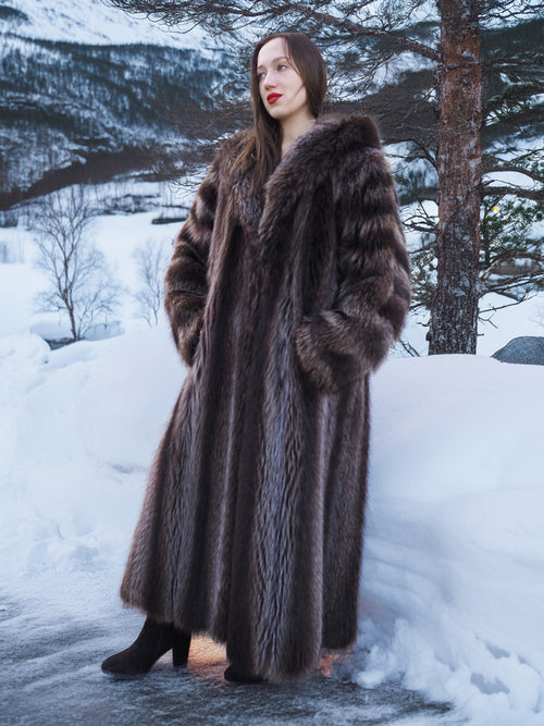 Silver Tip Canadian Raccoon Fur Coat styled in snowy forest. Warm and elegant full-length fur outerwear for winter.