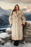 Woman in a fur coat standing in a snowy mountain landscape