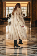 Person wearing a long fur coat in an elegant interior setting