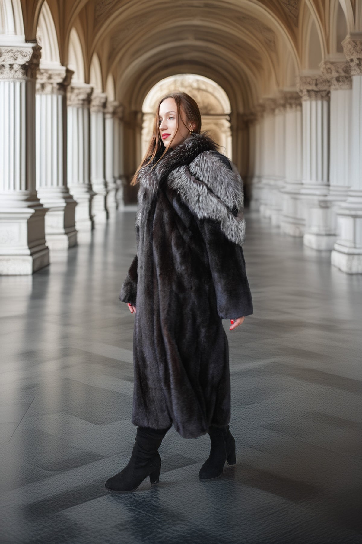 A woman wearing a long black fur coat with a gray fur collar stands in a grand, arched hallway with stone columns.