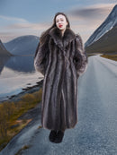 Full-length raccoon fur coat with wide collar, modeled on mountain road with fjord view, ideal for high-end winter outerwear.