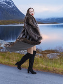 Model twirling in full-length raccoon fur coat beside reflective lake, highlighting plush texture and luxury winter style.