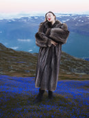 Real fur raccoon coat in silver tips, full-length and warm, modeled in alpine field with blue flowers, luxury winter apparel.