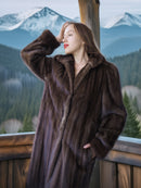 Woman wearing a brown fur coat with a mountainous landscape in the background