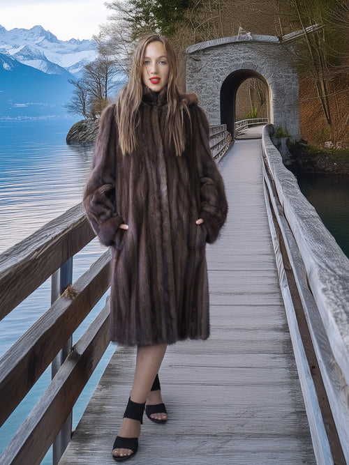 Woman in a fur coat standing on a wooden bridge over a lake with mountains in the background