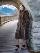 Woman in a fur coat standing on a wooden bridge with mountains in the background