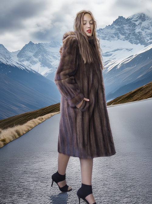 Woman in a fur coat standing on a road with mountains in the background