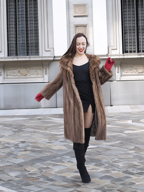 Model dancing in vintage pastel Canadian brown mink fur coat over black mini dress, perfect for stylish and playful winter fashion.