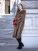 Model leaning against stone wall in vintage pastel Canadian brown mink fur coat, ideal for luxury outerwear and timeless fashion appeal.