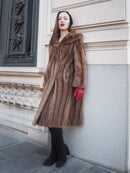 Vintage pastel Canadian brown mink fur coat styled with red gloves, leaning against architectural wall, perfect for winter fashion statements.