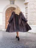 Back view of woman in flowing dark fur coat, urban setting