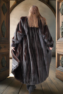 Person wearing a fur coat walking through a wooden archway.