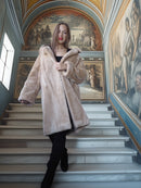 Woman in a fur coat standing on a staircase with classical frescoes in the background