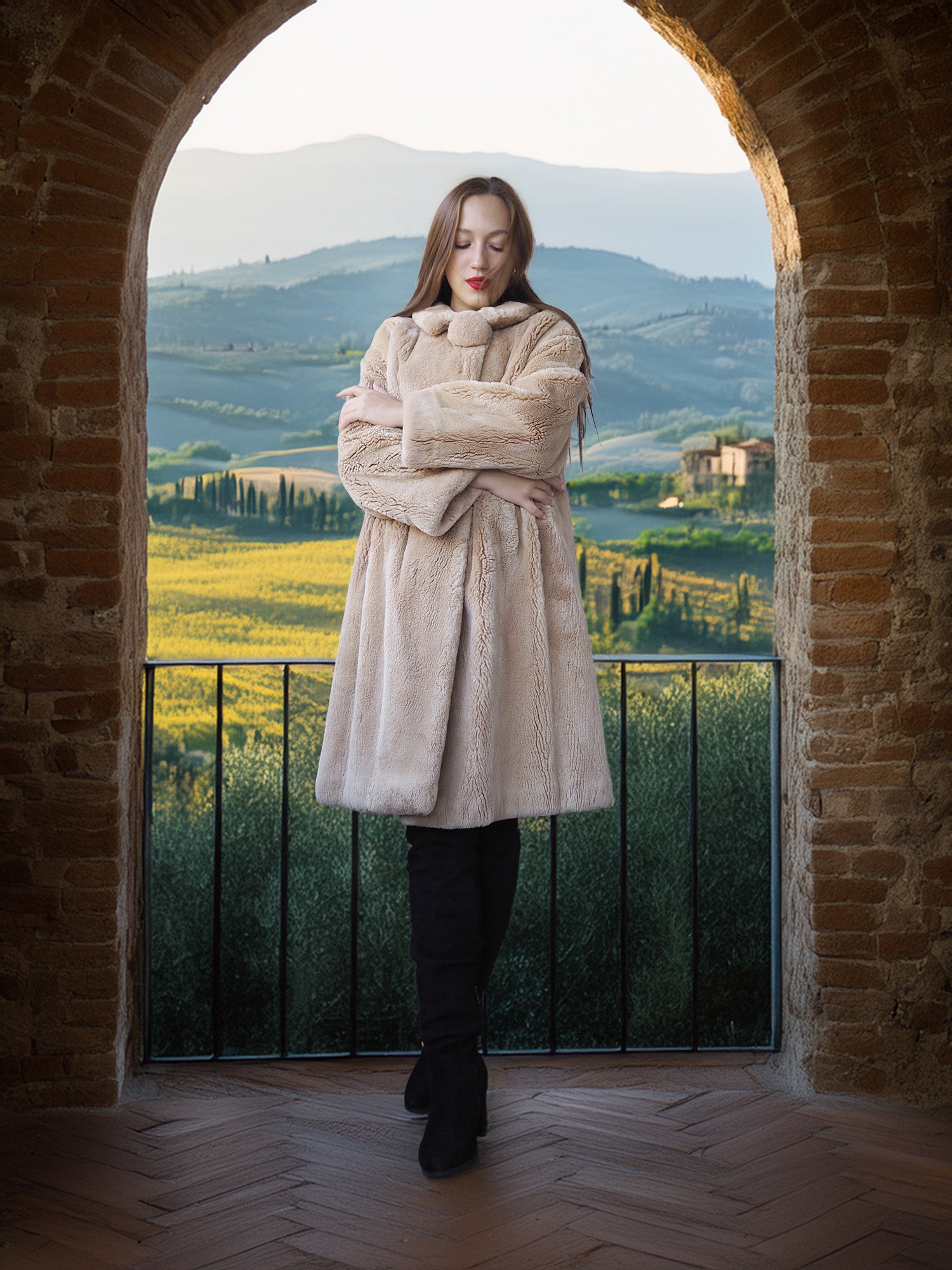 Woman in a beige coat standing in an archway with a scenic view of rolling hills and fields.